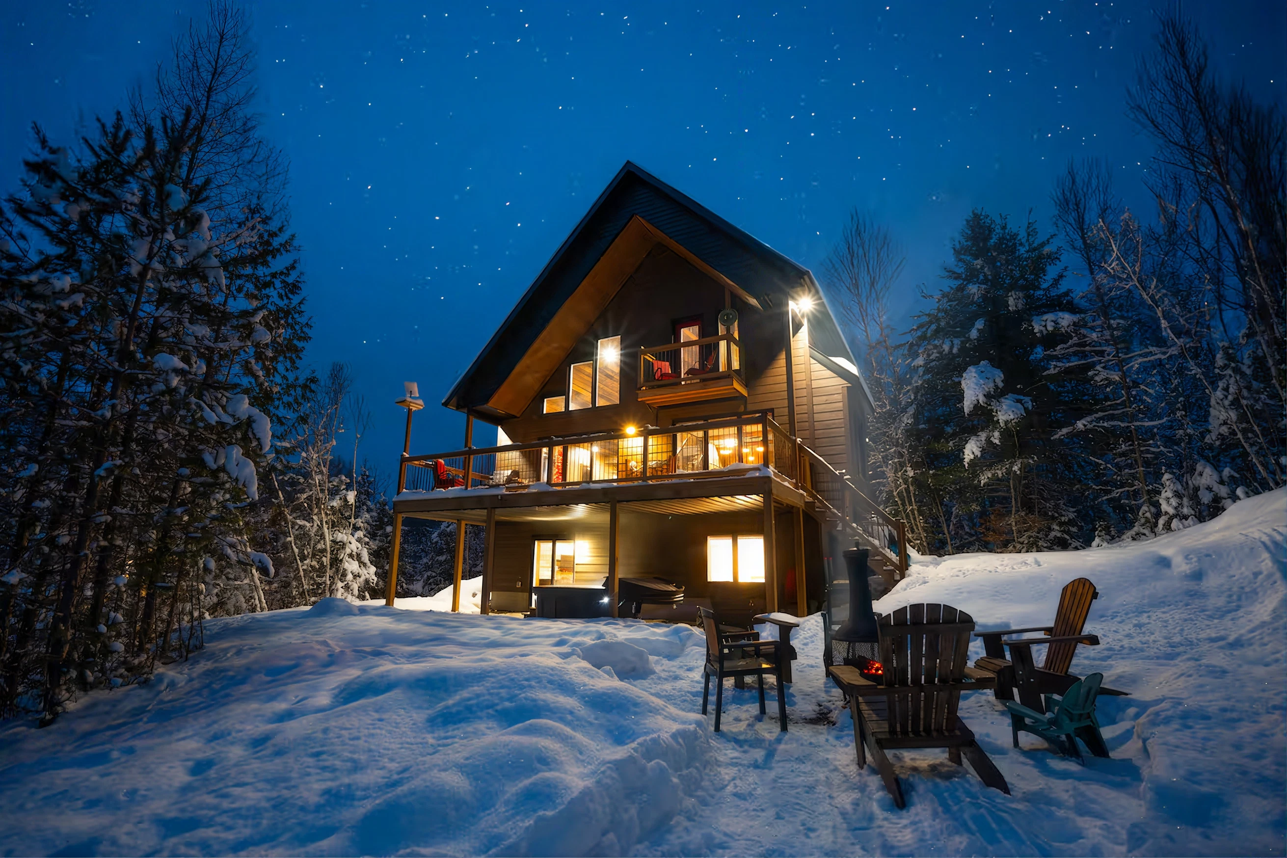 Un chalet illuminé sous les étoiles, entouré de neige